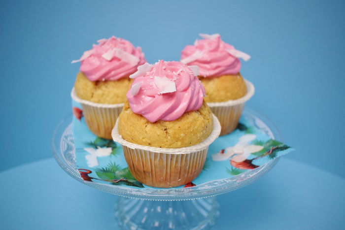 a photo of three cupcakes with pink frosting