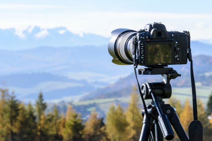 A camera on a tripod with a mountain landscape