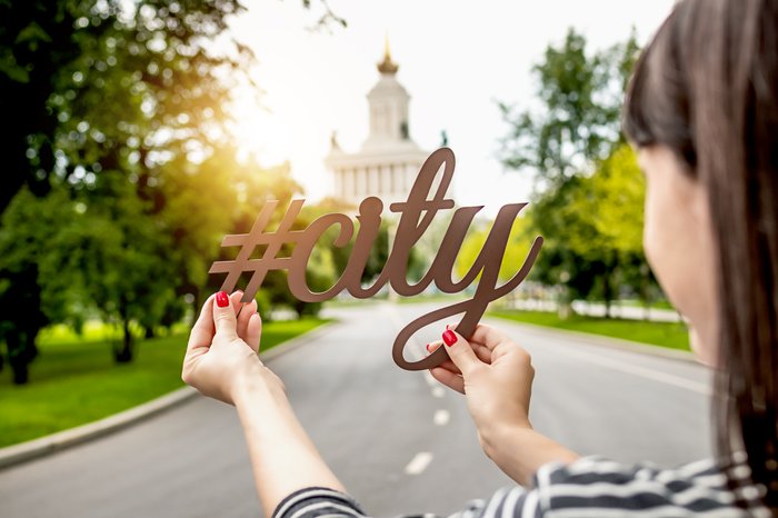 A girtl holding a gold instagram cutout that says 'city'