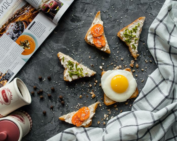 photo of different toasts with a checkered tablecloth, a magazine coffee beans on a table