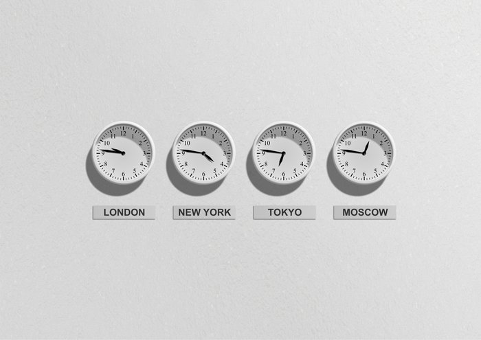 Four white clocks set to London, New York, Tokyo, Moscow Timezones