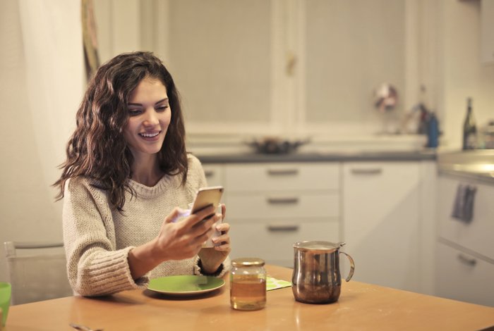 A girl using her cellphone at the breakfast table 