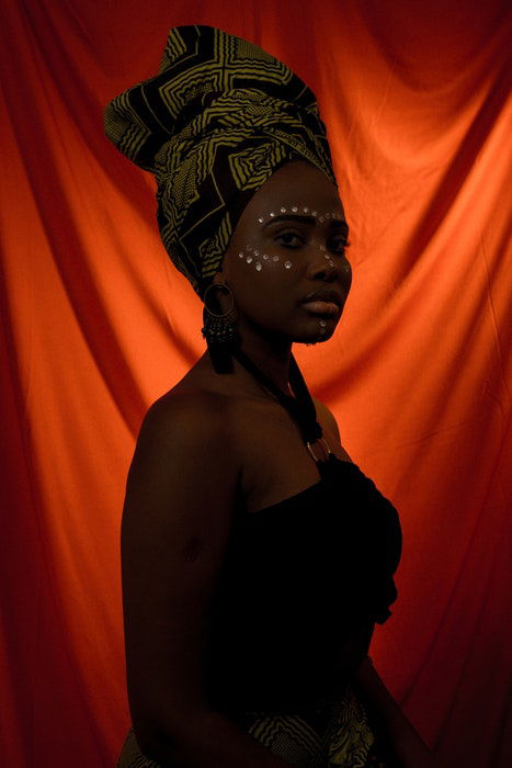 A dark studio photo of a woman against a backlit red sheet using a 1 light setup for portraits