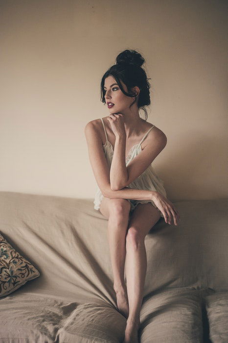 A girl in white lingerie posing on a couch for a bridal boudoir photoshoot