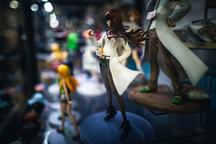 A plastic figure of a woman on a shelf with other toys