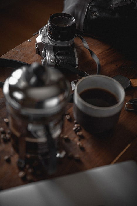 Photo of a camera and a mug of coffee on a wooden table