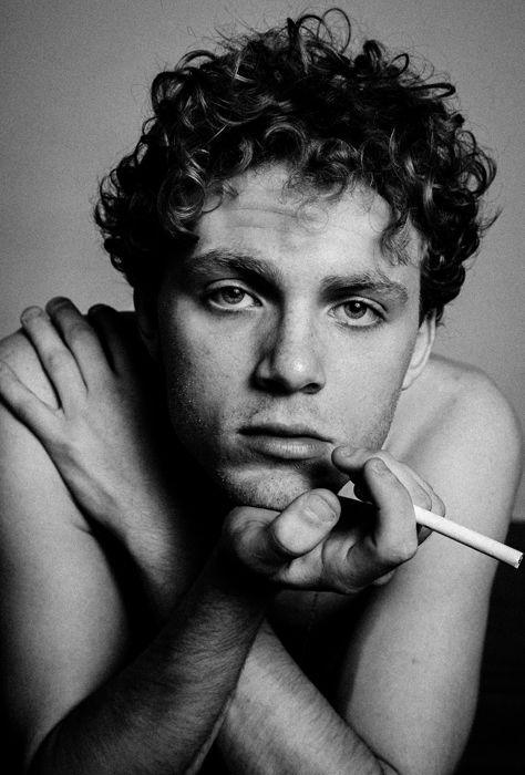 A black-and-white photo of a young man smoking a cigarette using a 1 light setup for portraits