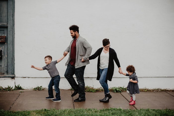 A couple with two young kids holding hands outdoors