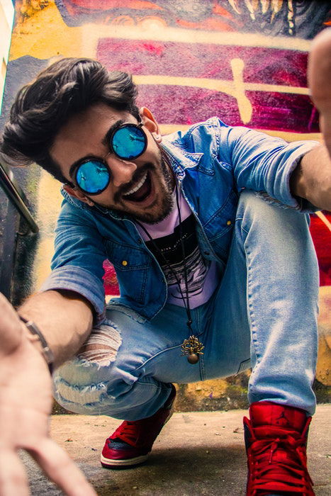 A young man posing for a selfie in front of colorful graffiti