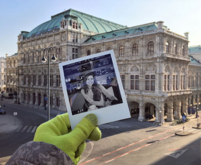 A Polaroid photograph of a smiling girl held in front of the Viennese Opera House in the background