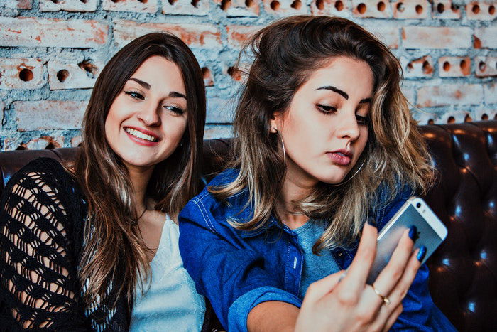 Two young women posing for a selfie while sitting