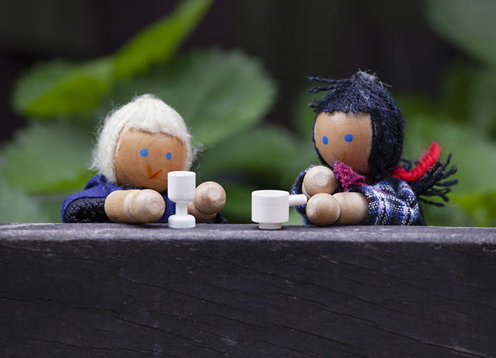 Cute toy photography of two wooden dolls dressed as old women drinking tea