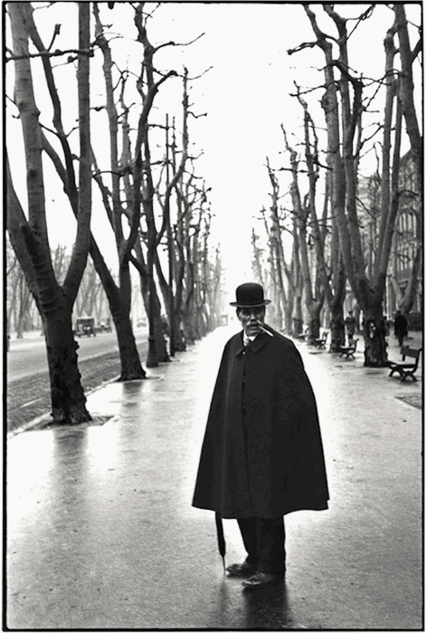 a black and white henri cartier-bresson image of a man within two rows of trees