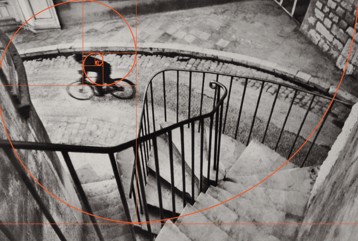 a black and white henri cartier bresson of a cyclist shot from above with fibonacci spiral overlay