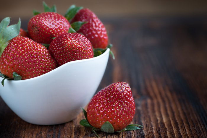 A bowl of strawberries on a table.