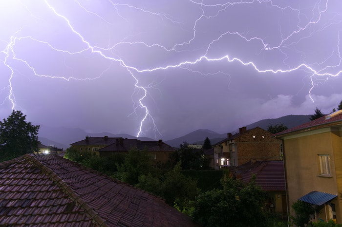 Forked lighting striking over a housing estate at night