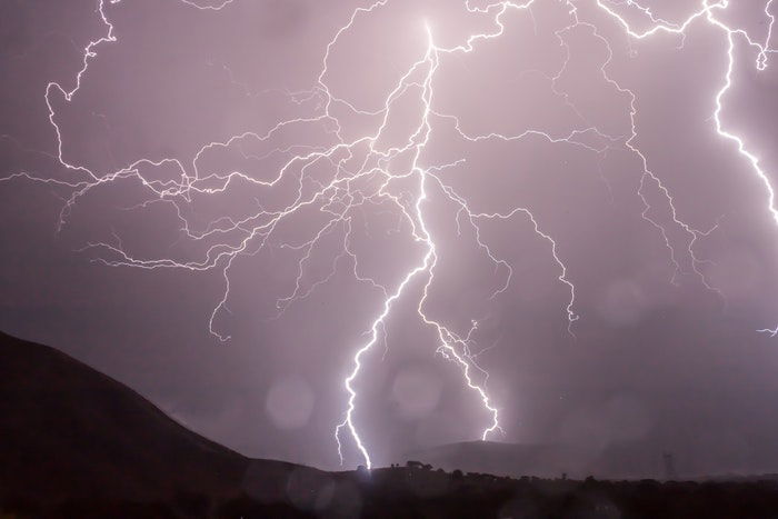 Forked lighting striking over a landscape at night