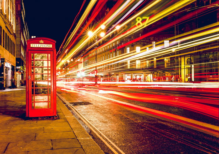 The vibrant nightlife of a city, with the famous Big Ben clock tower and red double-decker bus in motion on a busy street. 