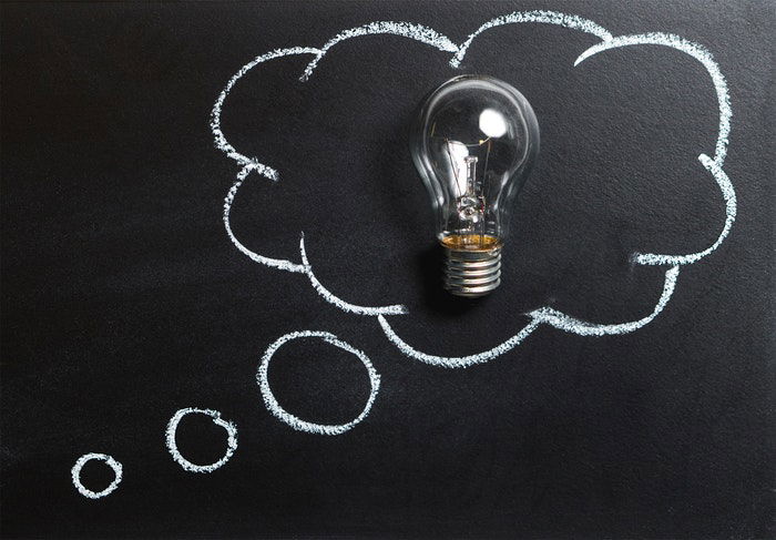 A lightbulb on top of a blackboard drawing of a thought bubble