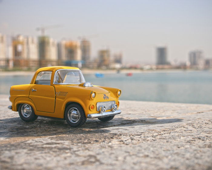 A toy yellow taxi car on a wall