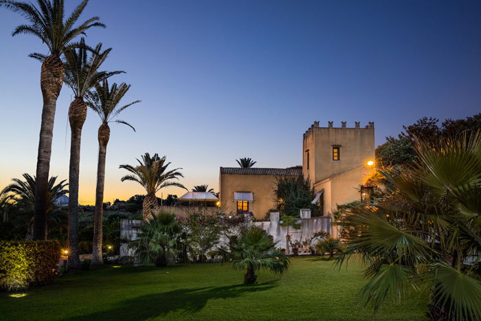 a twilight photo of a castle like house in a tropical location