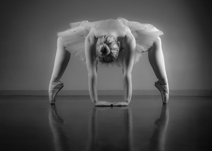 Graceful ballerina warming up in black and white in the ballet studio