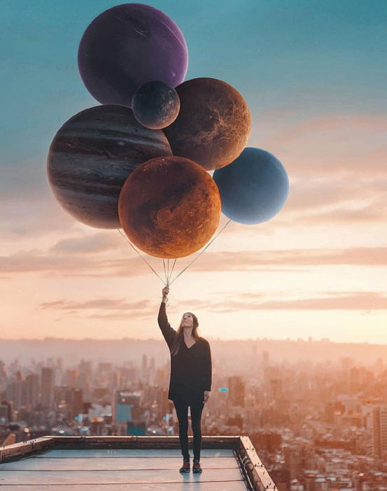 Fine art photo of a girl holding planets as balloons