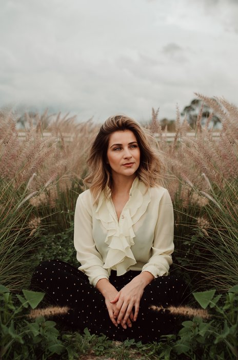 a cloudy day portrait photograph of a woman sitting in a wheat field