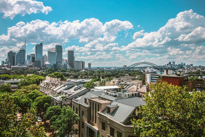 wide angle image of a city street with skyline in the background and blue skies with clouds above