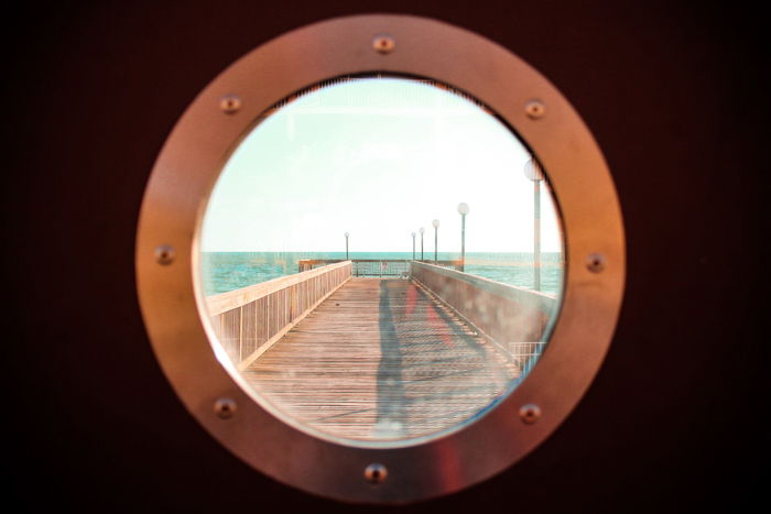 View of a pier through a boat porthole