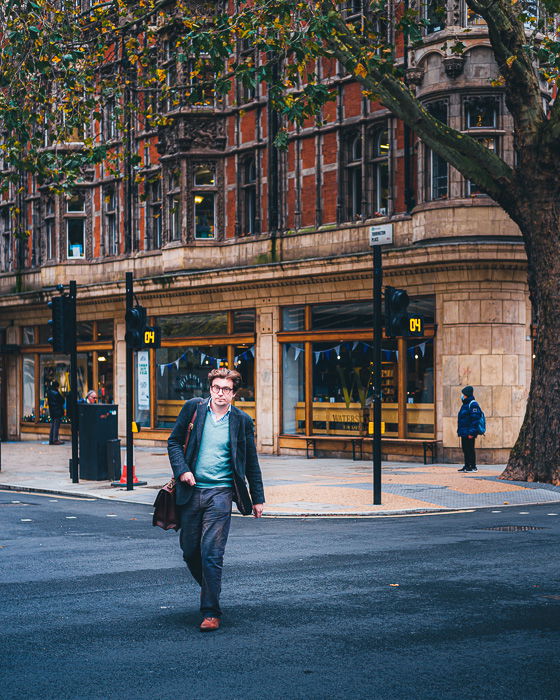 A man walking down a city street in a business suit.