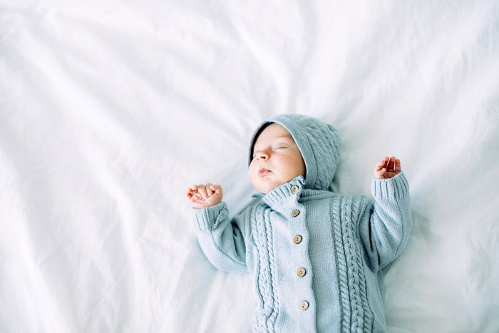 A baby sleeping on a white bed. 