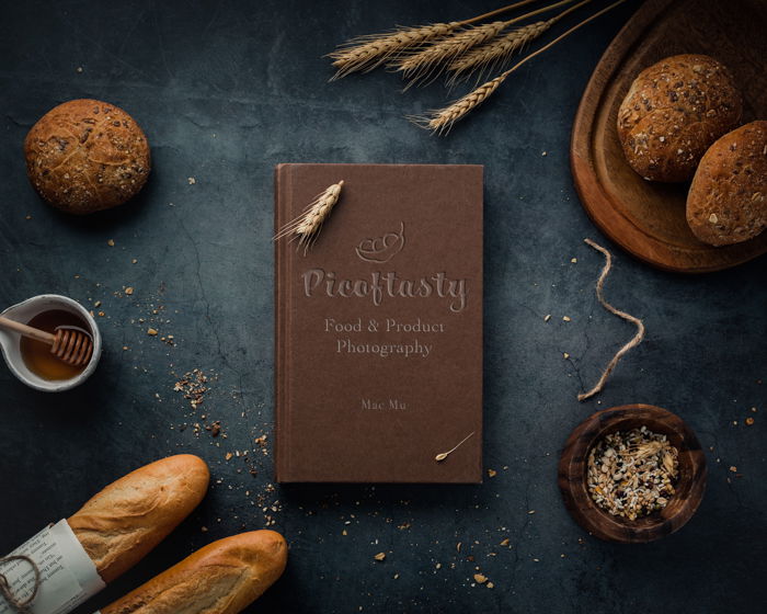 Product photography overhead image of a cookbook on a table with bread and wheat