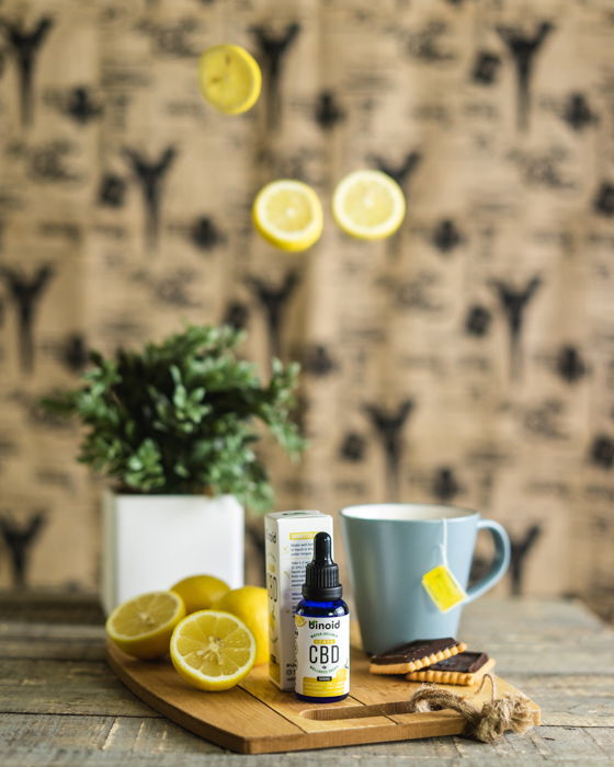 Product photography lifestyle image of a CBD bottle on a dining room table and lemons suspended in the air