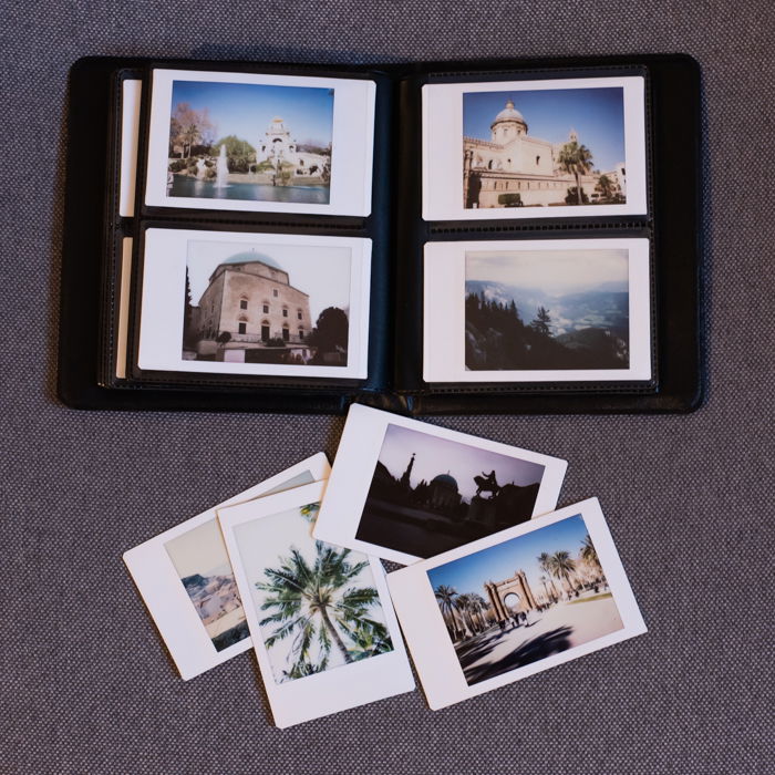 an overhead photo of a fujifilm instax mini 8 photo album with printed instant photos inside and outside