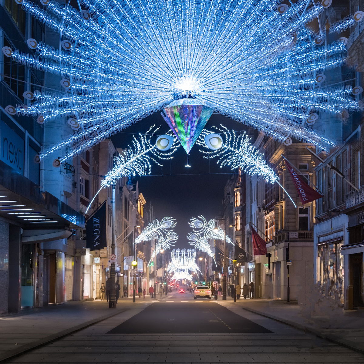 An illuminated street scene with a large decorative light fixture that resembles a flower.