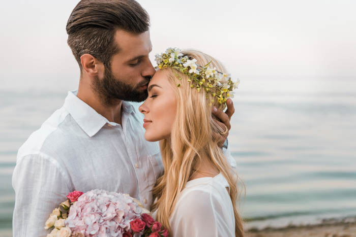 A groom giving a kiss onto the bride's forehead