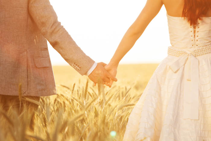 A picture of a bride and groom holding each other's hand