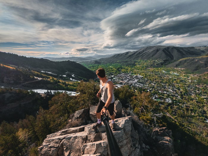 adventure photography of a man with a gopro on a stick looking out toward a valley