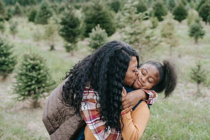 mother kissing daughter in grassy area