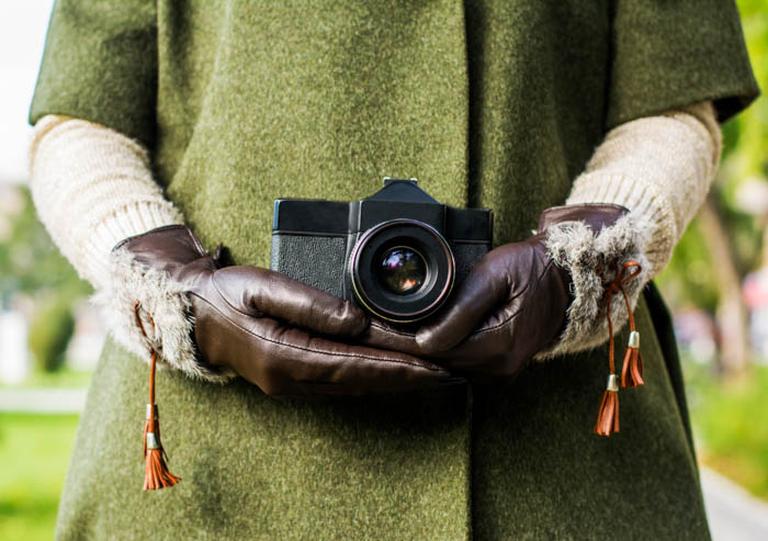 an image of a person holding a camera with a set of brown gloves on