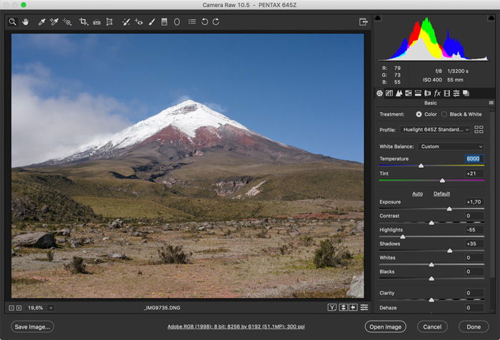 A computer screen displaying a photo editing software with an edited image of a volcano covered in snow and cloudy skies.