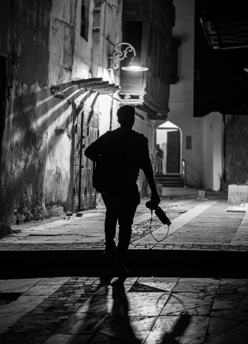 black and white silhouette of a photographer near a street light