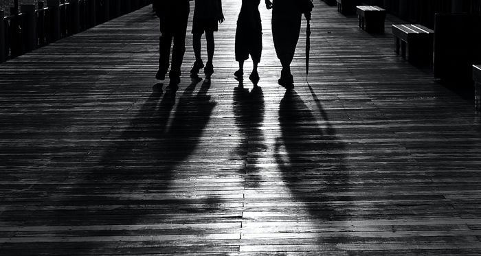 black and white image of four people waist-down and with shadows