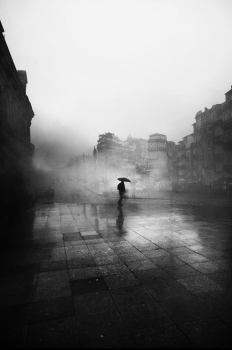 A rainy day scene in an urban area with a person holding an umbrella.