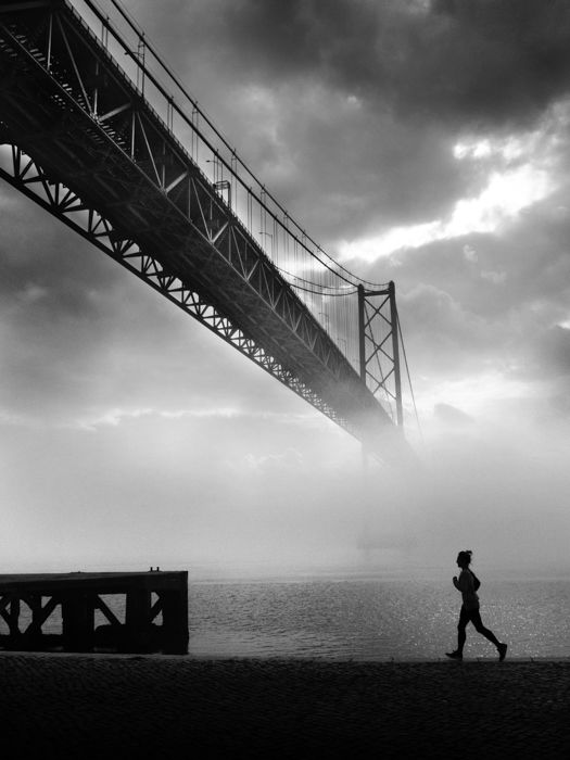 black and white image of a runner with the misty Golden Gate in the background