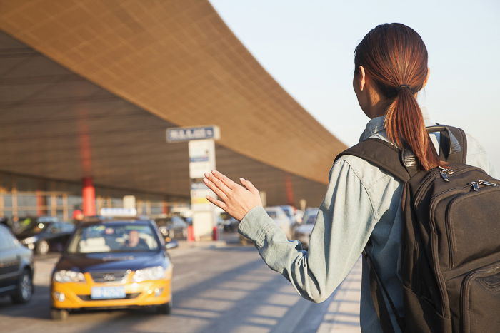 an image of a woman hailing a taxi at the airport