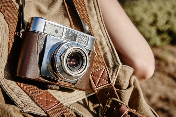 An image of a vintage camera on a leather backpack