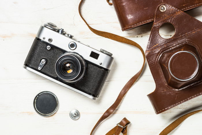 A vintage analog camera in leather casing and its accessories on a table