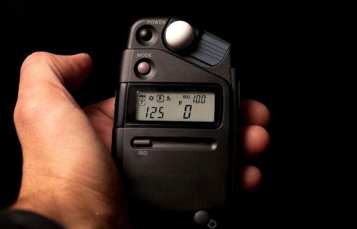 a mans hand holding a light meter